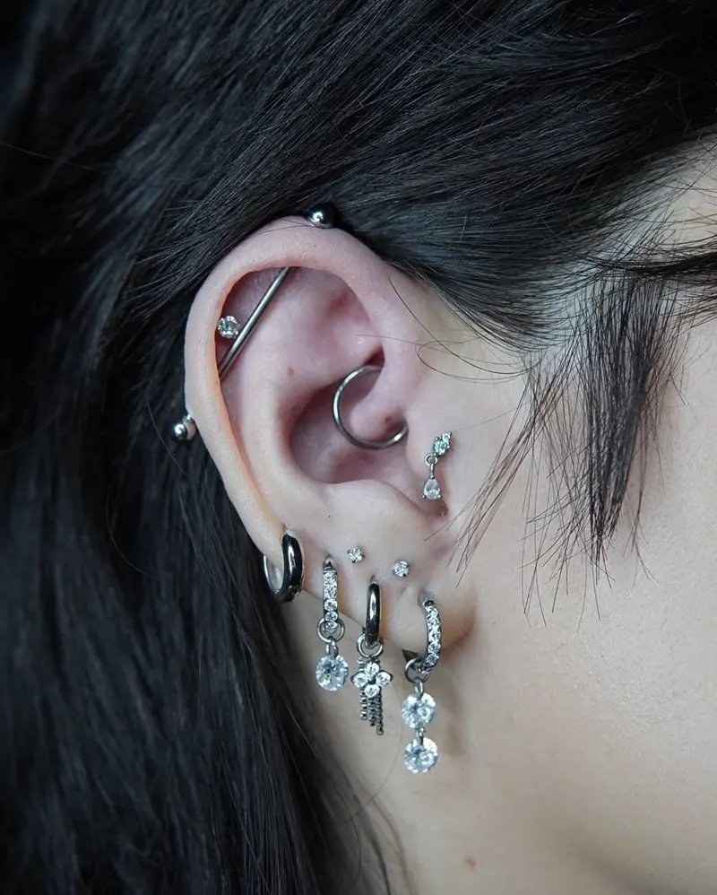 Curated ear stack — industrial, helix, conch and stacked lobes — piercing by Foenix Ink, Hollywood FL, implant-grade titanium (1/5)