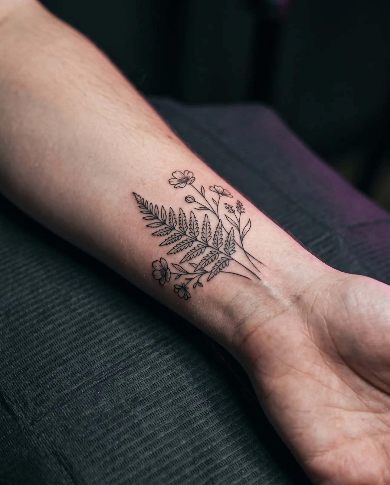 Close-up of a small healed fine-line botanical tattoo on a wrist