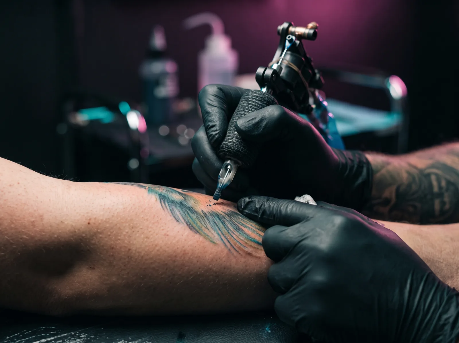 Tattoo artist shading a color realism forearm piece mid-session