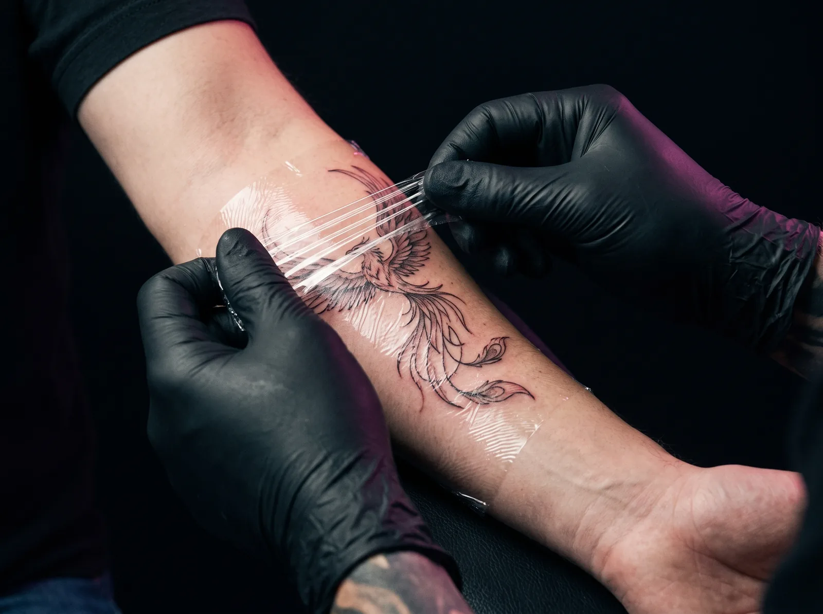 Artist applying protective wrap to a freshly finished tattoo