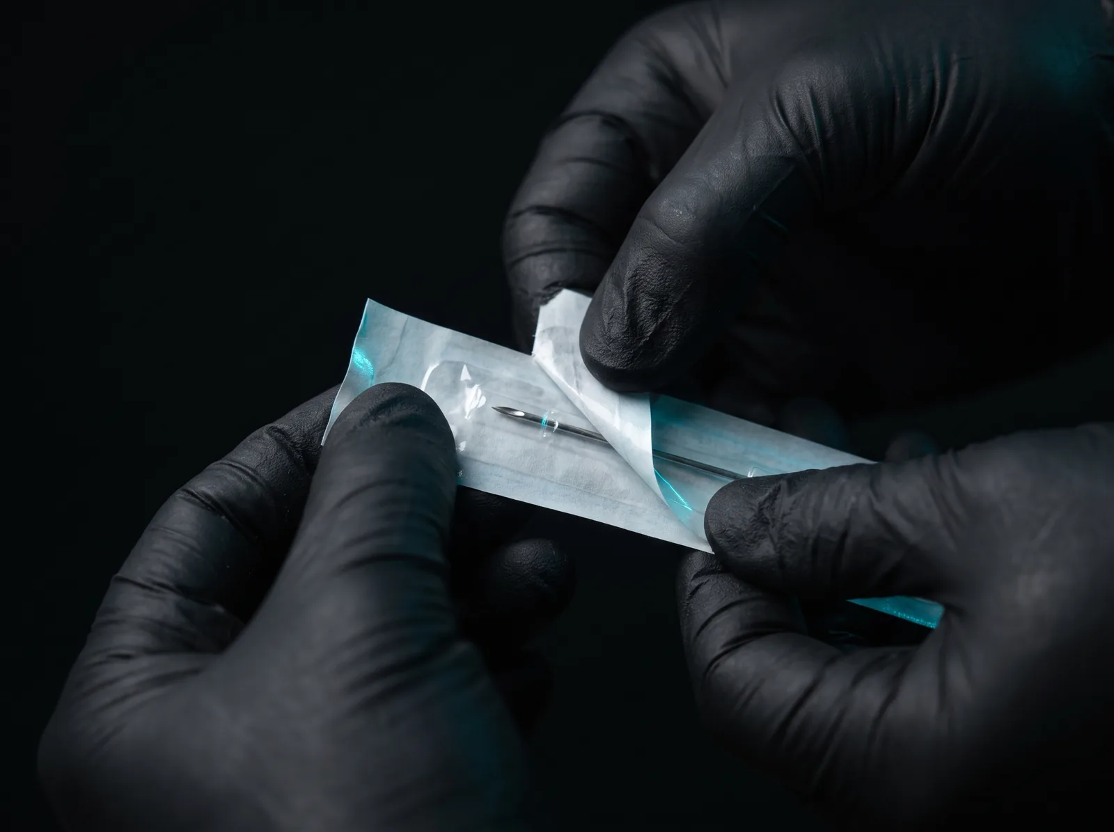 Piercer preparing a sealed single-use needle before an ear piercing