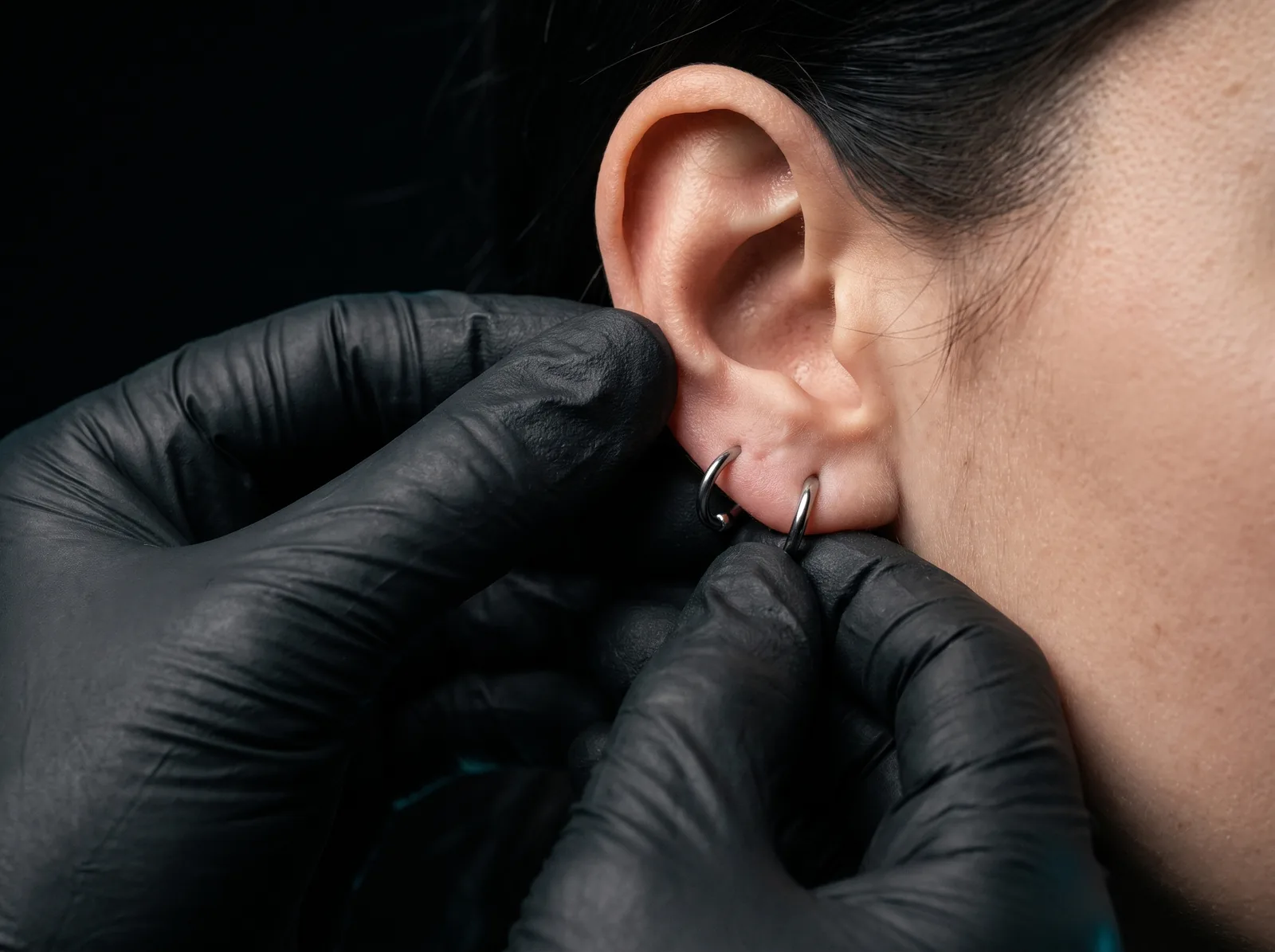 Piercer gently checking jewelry fit during a healing check-in