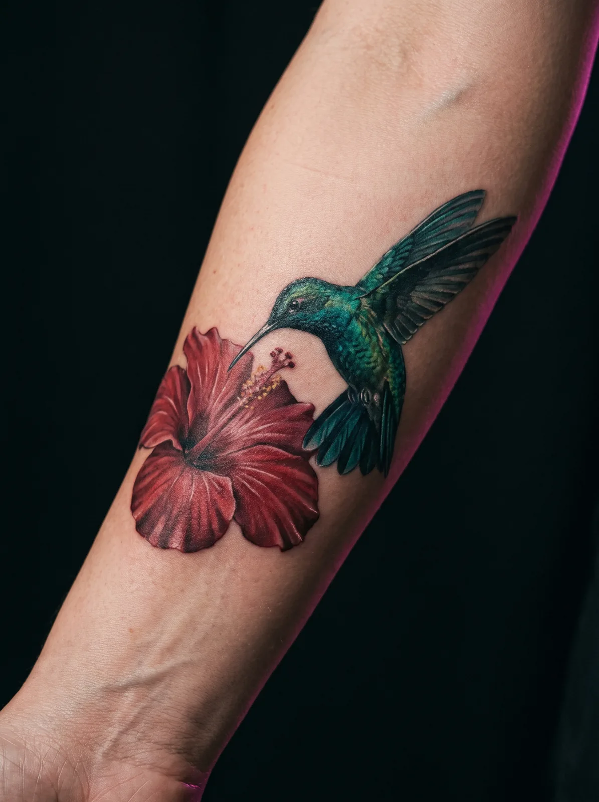 Healed color realism tattoo of a hummingbird and hibiscus flower on a forearm