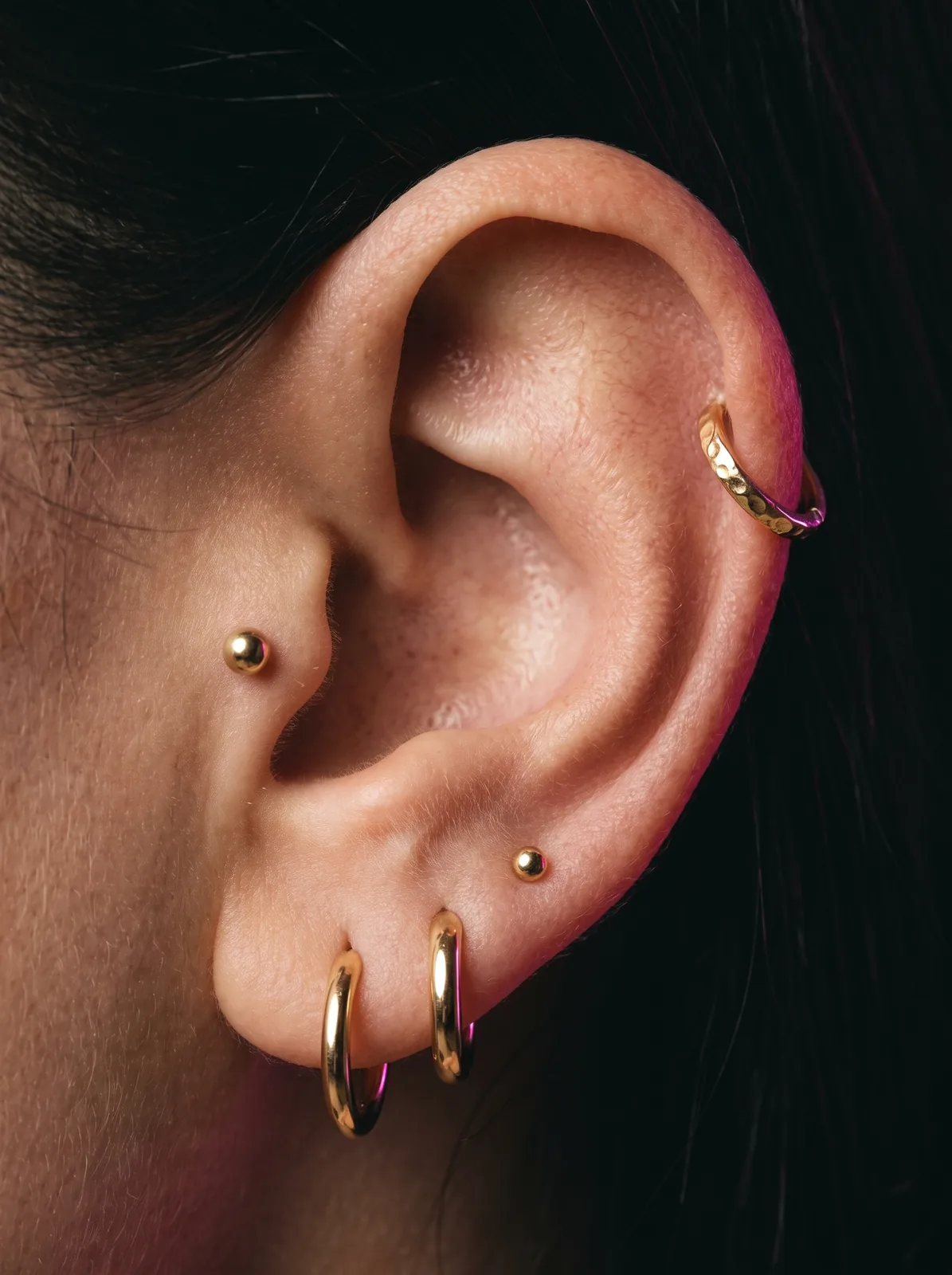 Healed curated ear stack with lobe, helix, and tragus piercings styled in gold jewelry