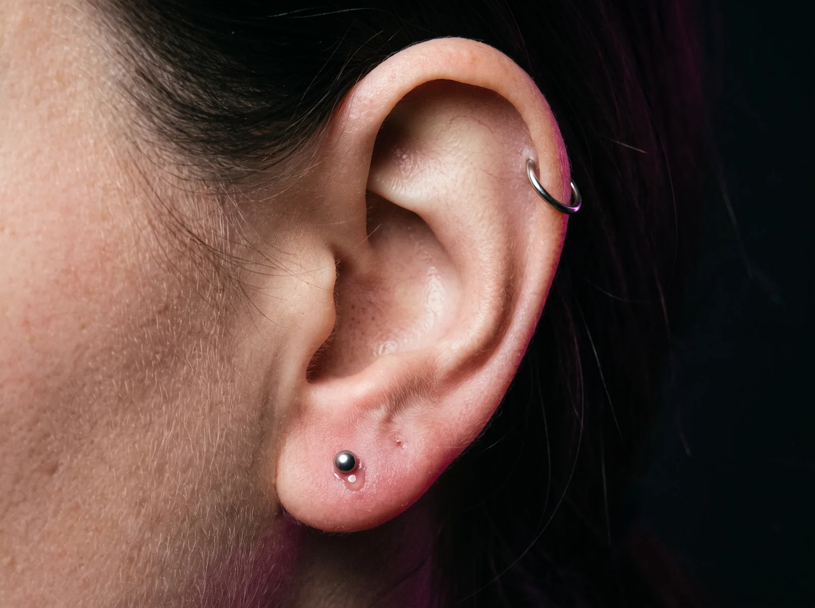One ear showing a fresh lobe piercing next to a fully healed helix piercing