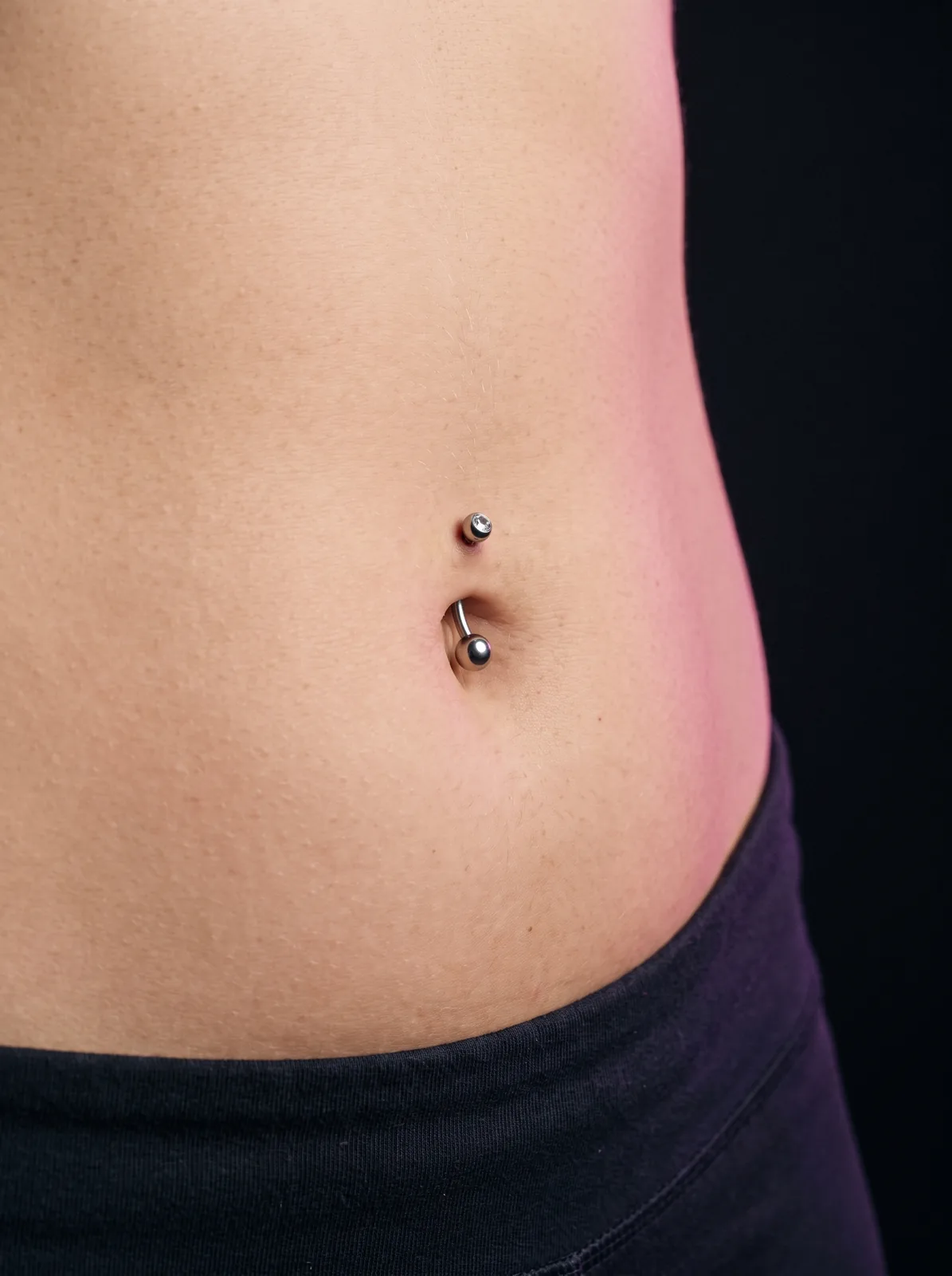 Close-up of a healed navel piercing with a titanium curved barbell