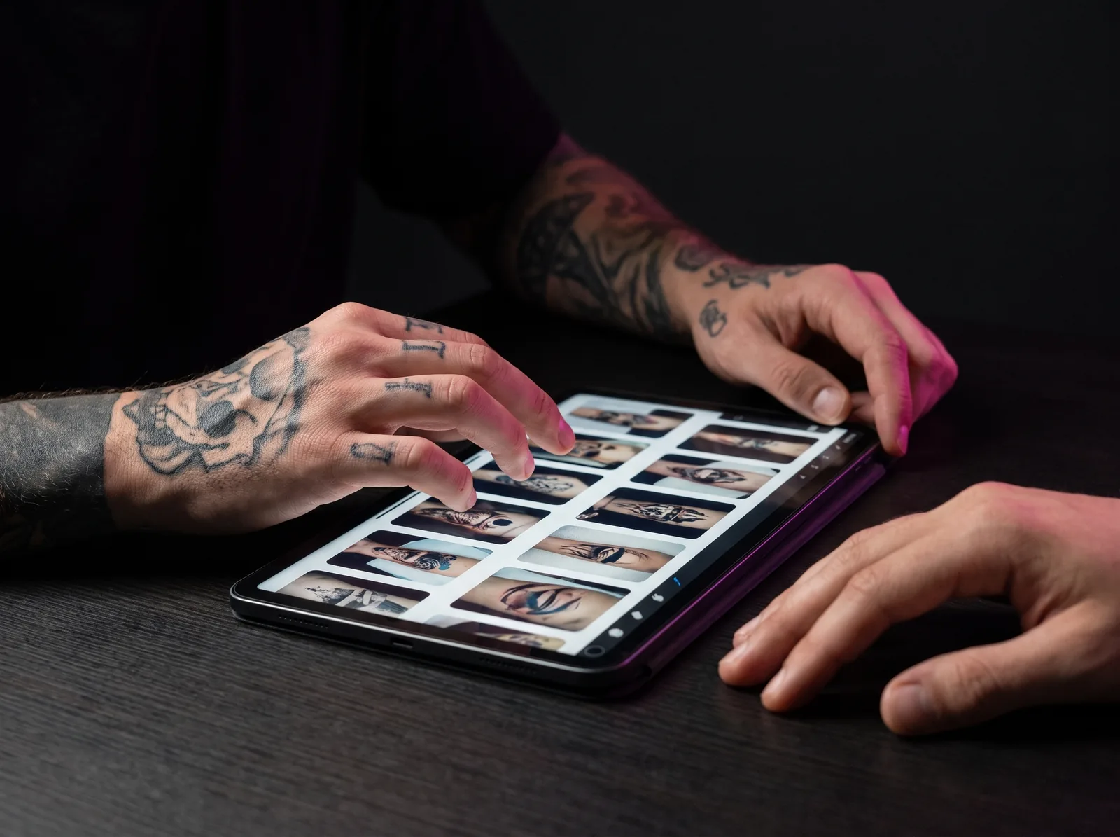 Hands reviewing tattoo reference photos on a tablet during a consultation