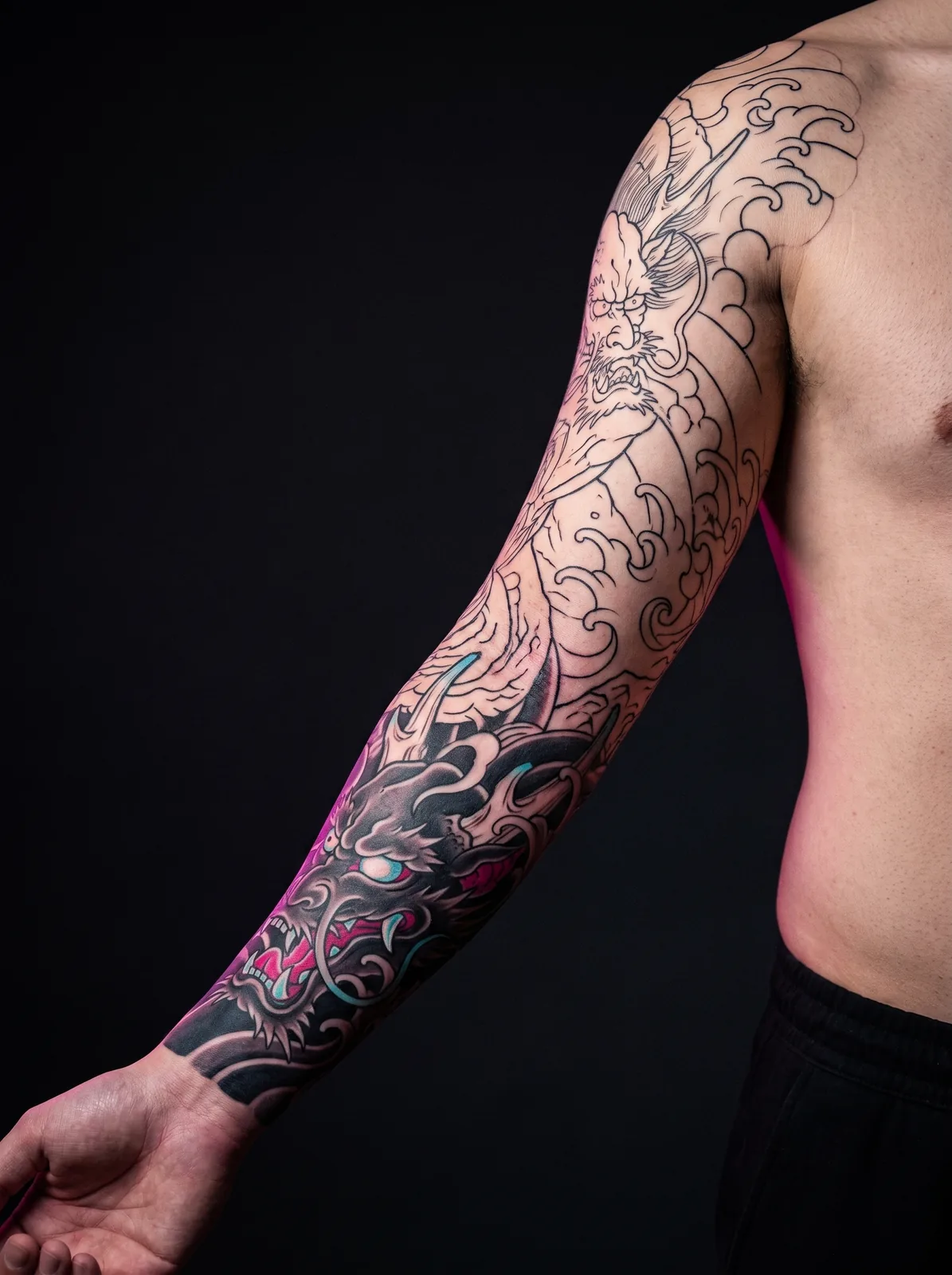 Large tattoo sleeve project mid-progress, with linework complete and shading finished on part of the piece